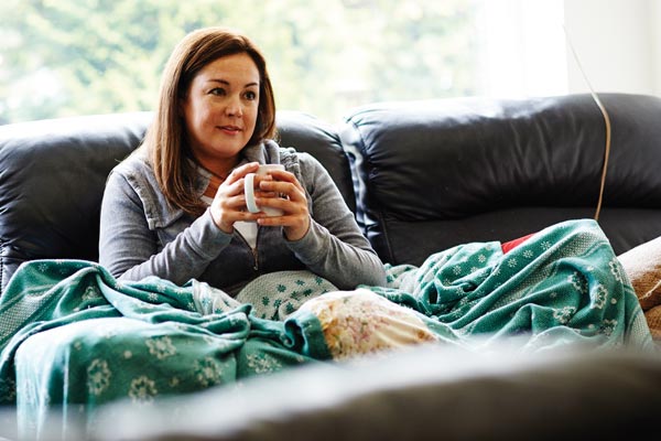 A woman sitting on couch with cup of tea
